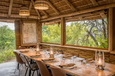 a large wooden table in a room with windows at Bundox Explorer Camp in Hoedspruit