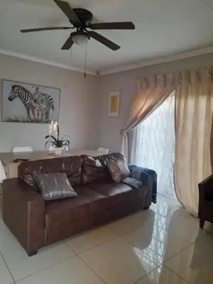 a living room with a brown couch and a ceiling fan at Tumi's Home away- 3 Bedroom in Witbank