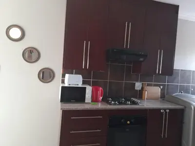 a kitchen with wooden cabinets and a counter top with a microwave at Tumi's Home away- 3 Bedroom in Witbank