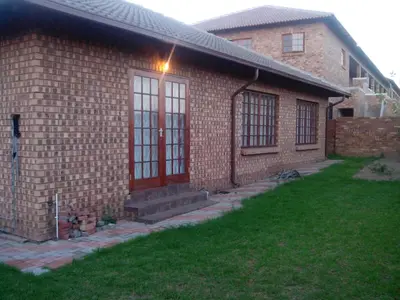 a brick house with a red door and a yard at Tumi's Home away- 3 Bedroom in Witbank