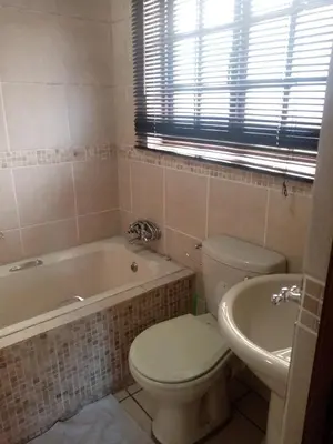 a bathroom with a toilet and a tub and a sink at Tumi's Home away- 3 Bedroom in Witbank