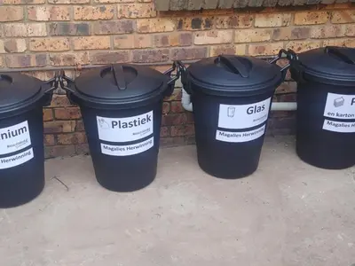 four black trash cans lined up against a brick wall at Grace Place BnB Pretoria in Pretoria