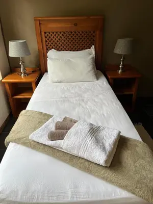 a white bed with a towel on it with two lamps at Grace Place BnB Pretoria in Pretoria