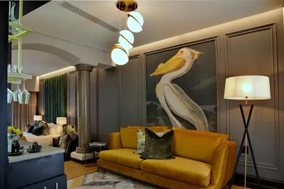 a living room with a yellow couch and a painting of a bird at Apogee Boutique Hotel & Spa in Pretoria