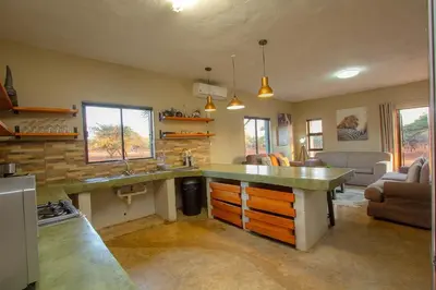 a kitchen with a large counter and a living room at Doornkom in Marloth Park