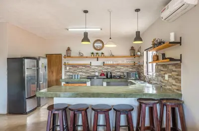 a kitchen with a counter with bar stools at Doornkom in Marloth Park
