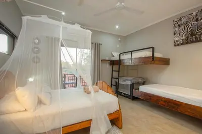 a bedroom with two bunk beds and a window at Doornkom in Marloth Park