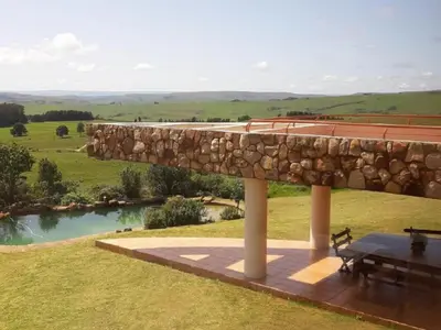 a stone wall next to a picnic table and a lake at Amberley Mountain Reserve in Dullstroom