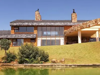 a house on a hill next to a body of water at Amberley Mountain Reserve in Dullstroom