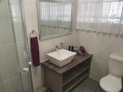 a bathroom with a sink and a toilet and a mirror at Karee Laagte in Leeuwfontein