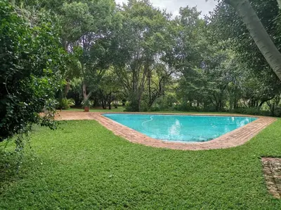 a swimming pool in a yard with grass and trees at Karee Laagte in Leeuwfontein