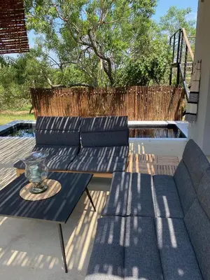 a patio with two couches and a table on a deck at Birdsong Kruger in Marloth Park