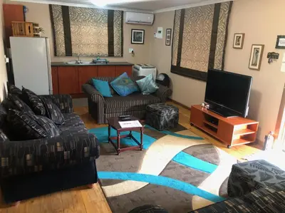 a living room with two couches and a flat screen tv at Luxury Treetop Lodge in Marloth Park