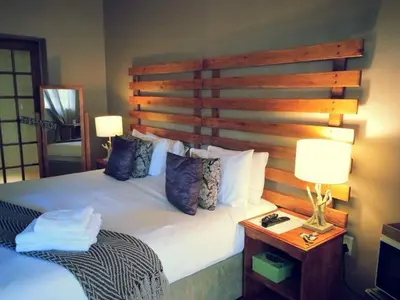 a bedroom with a large bed with a wooden headboard at Midrand Wild Goose Guest House B&B in Midrand