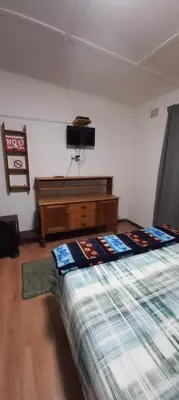a bedroom with a bed and a tv on the wall at Guesthouse 914 in Sabie