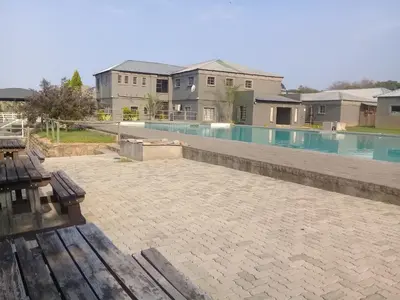 a swimming pool with a bench and some buildings at SIMA SILVER LODGE in Tzaneen