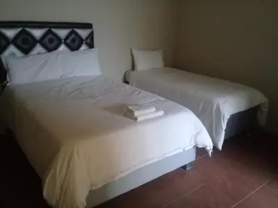 two beds in a hotel room with white sheets at SIMA SILVER LODGE in Tzaneen