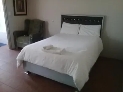a bedroom with a large white bed and a chair at SIMA SILVER LODGE in Tzaneen