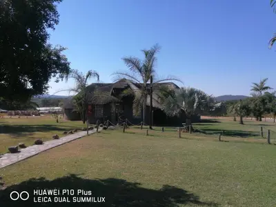 a house with a thatched roof in a park at SIMA SILVER LODGE in Tzaneen