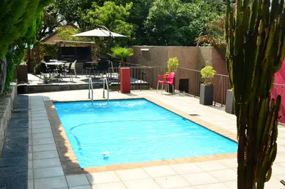 a swimming pool in a yard with a table and chairs at RAMATA GUEST HOUSE in Pretoria