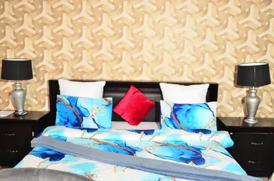 a bedroom with a bed and two lamps and a wall at RAMATA GUEST HOUSE in Pretoria