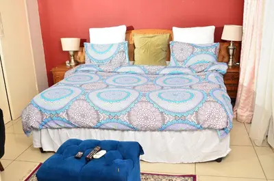 a bedroom with a bed with a blue comforter and pillows at RAMATA GUEST HOUSE in Pretoria