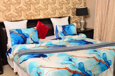 a bed with a blue comforter and pillows at RAMATA GUEST HOUSE in Pretoria