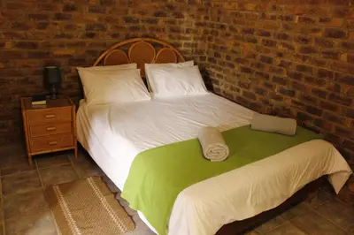 a bedroom with a bed and a brick wall at El Rancho Grande in Warmbaths