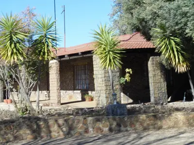 a stone house with palm trees in front of it at El Rancho Grande in Warmbaths