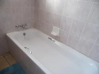 a white bath tub in a tiled bathroom at El Rancho Grande in Warmbaths