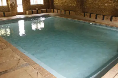 a swimming pool with blue water in a building at El Rancho Grande in Warmbaths
