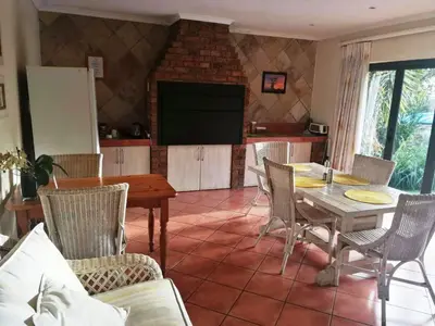 a dining room with a table and chairs and a television at Feather Tree Bed and Breakfast in Centurion