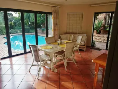 a dining room with a table and chairs and a pool at Feather Tree Bed and Breakfast in Centurion