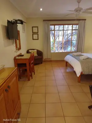 a bedroom with a bed and a table and a couch at Feather Tree Bed and Breakfast in Centurion