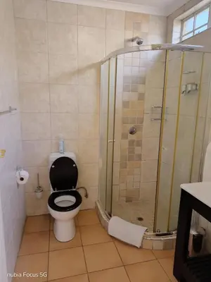 a bathroom with a shower with a toilet and a sink at Feather Tree Bed and Breakfast in Centurion
