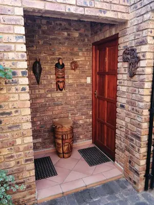 a brick wall with a wooden door and a barrel at Feather Tree Bed and Breakfast in Centurion