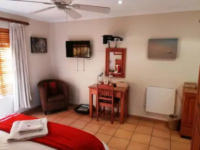 a bedroom with a bed and a desk and a chair at Feather Tree Bed and Breakfast in Centurion