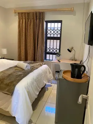 a bedroom with a bed and a desk and a television at Hush Guest House in Northam