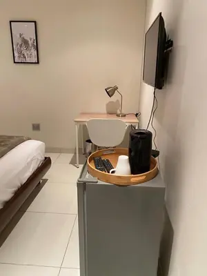 a room with a bed and a desk with a television at Hush Guest House in Northam
