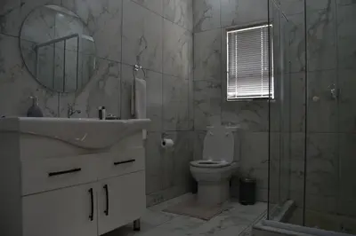 a bathroom with a sink and a toilet and a mirror at Hush Guest House in Northam