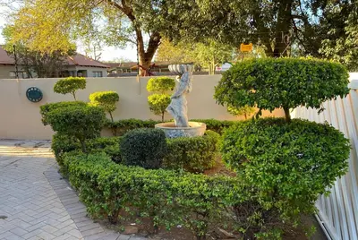 a statue in a garden with bushes and a fence at Hush Guest House in Northam