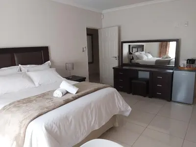 a bedroom with a large bed and a large mirror at Hush Guest House in Northam
