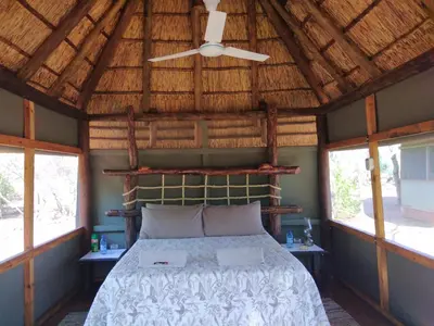 a bedroom with a bed with a wooden ceiling at Nthakeni Bush & River Camp in Pafuri Gate