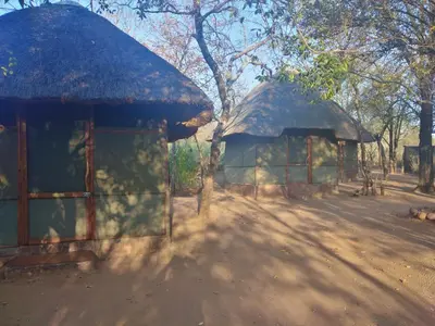 two houses with a thatched roof in a field at Nthakeni Bush & River Camp in Pafuri Gate