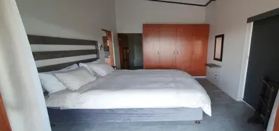 a bedroom with a large white bed and wooden cabinets at DaGama Dam - White River - Kestrel - House 21 in White River