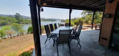 a table and chairs on a patio with a view of a river at DaGama Dam - White River - Kestrel - House 21 in White River