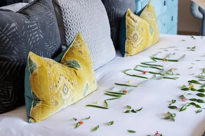 a bed with yellow pillows and flowers on it at Safari Moon Luxury Bush Lodge in Hoedspruit