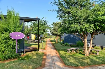 a sign in a park with benches and a tree at SleepOver Matoks in Matoks