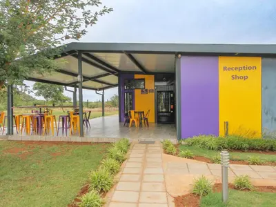 a yellow and purple building with tables and chairs at SleepOver Matoks in Matoks