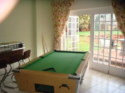 a room with a pool table in a room with a window at Heatherdale Guesthouse & Shuttle Services in Pretoria